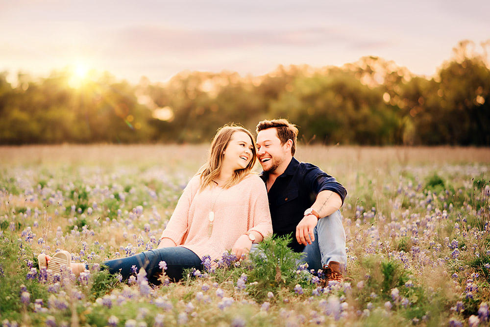 couple sitting in bluebonnet field in texas hill country