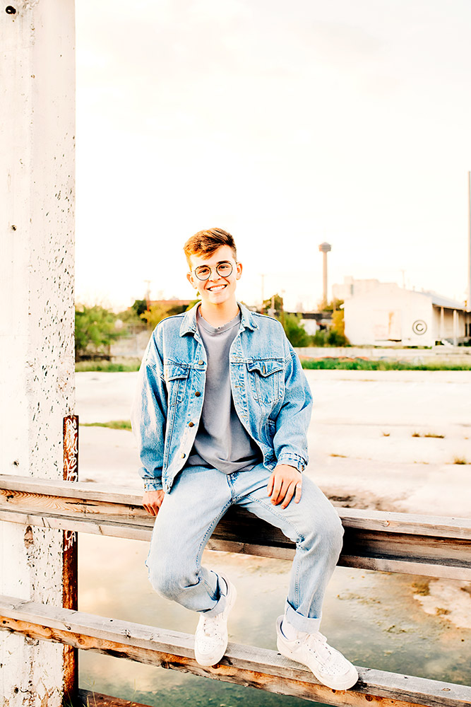teen boy sitting on fence smiling in san antonio texas